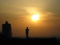 A religious person prays to God on a hill in front of the sun and sunset